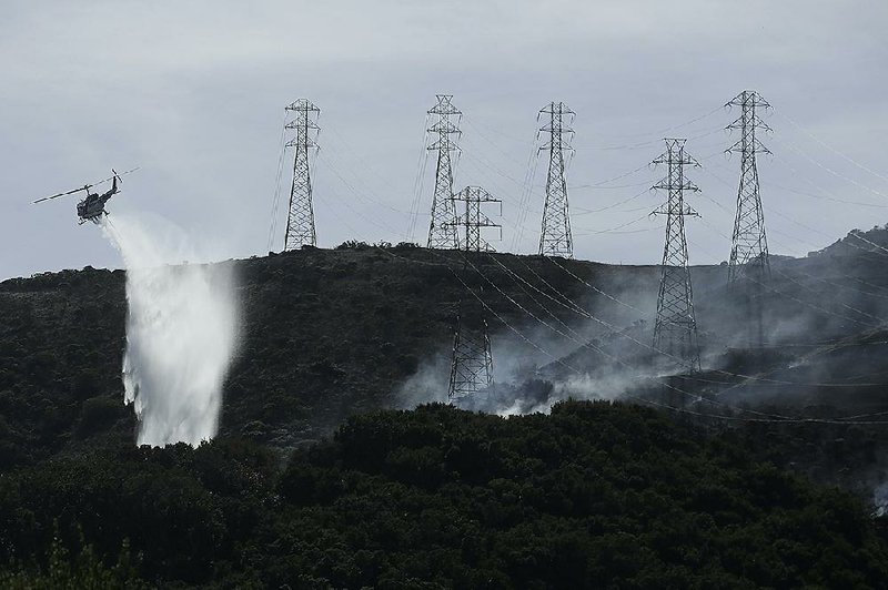 A helicopter drops water near power lines and electrical towers Thursday while working to extinguish a fire on San Bruno Mountain near Brisbane, Calif. More photos are available at arkansasonline.com/1011power/ 