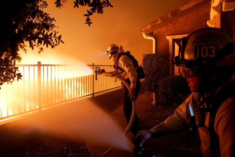 In this Thursday, Oct. 10, 2019 photo, Los Angeles City firefighters battle the Saddleridge fire near homes in Sylmar, Calif. (AP Photo/Michael Owen Baker)