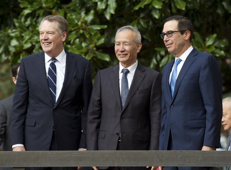 Chinese Vice Premier Liu He accompanied by U.S. Trade Representative Robert Lighthizer, left, and Treasury Secretary Steven Mnuchin, greets the media before a minister-level trade meetings at the Office of the United States Trade Representative in Washington, Thursday, Oct. 10, 2019. (AP Photo/Jose Luis Magana)