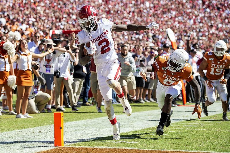 Oklahoma wide receiver CeeDee Lamb (2) avoids going out of bounds to score his third touchdown Saturday in front of Texas defensive back D’Shawn Jamison during the No. 6 Sooners’ 34-27 victory over the No. 11 Longhorns at the Cotton Bowl in Dallas.