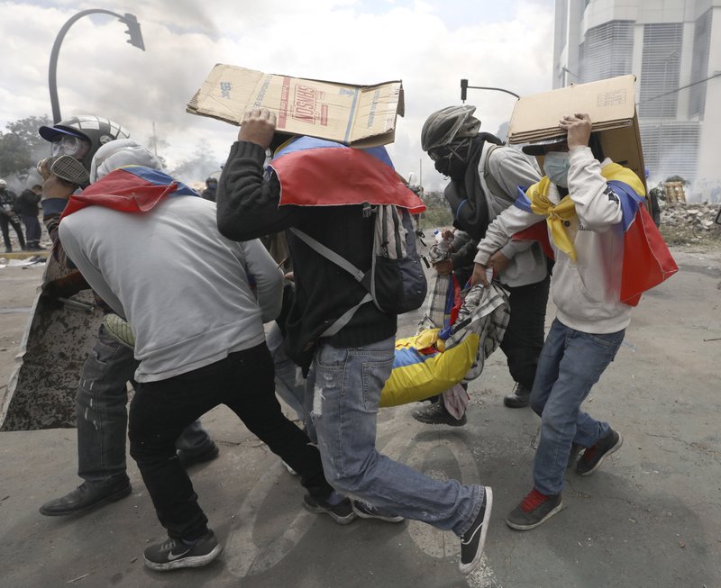 Anti-government demonstrators carry a wounded comrade away from the action during clashes with police in Quito, Ecuador, Saturday, Oct. 12, 2019. Protests, which began when President Lenin Moreno's decision to cut subsidies led to a sharp increase in fuel prices, have persisted for days. (AP Photo/Fernando Vergara)