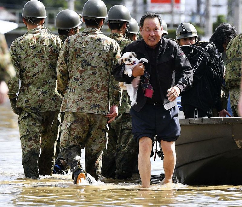 A man and his dog are rescued Sunday by forces in Motomiya, Japan, after the city was hit by Typhoon Hagibis. More photos are available at arkansasonline.com/1014japan/ 