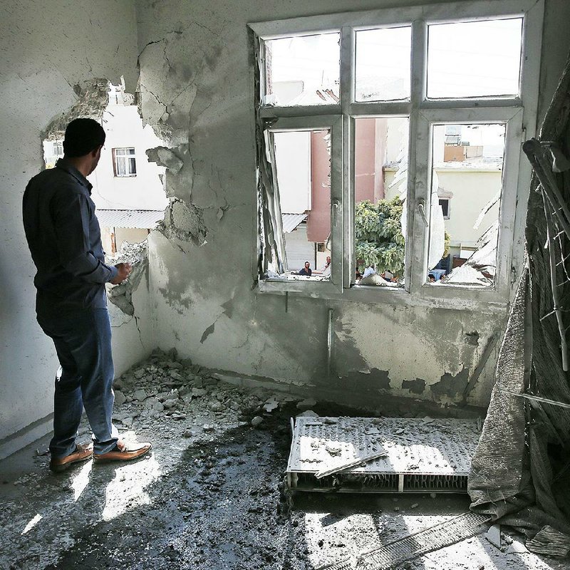 A person in Sanliurfa, Turkey, inspects a building damaged Sunday by a mortar round fired from Syria. More photos are available at arkansasonline.com/1014syria/ 