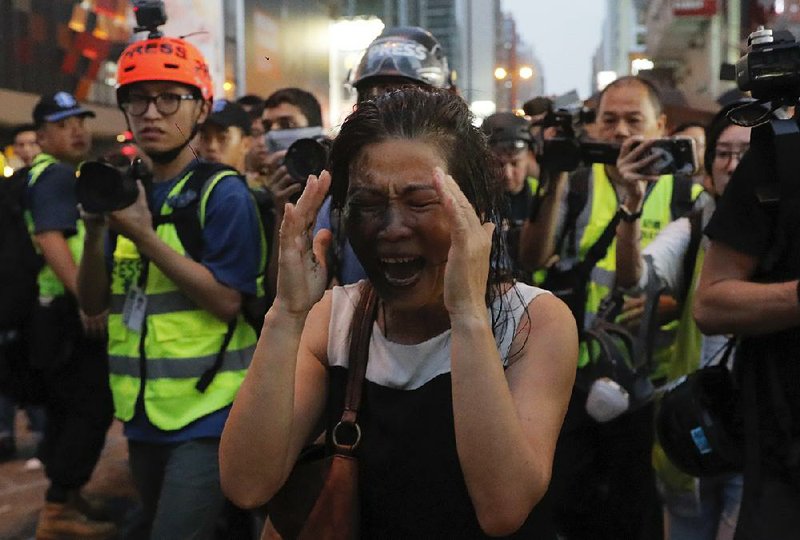 A woman reacts Sunday after Hong Kong protesters sprayed liquid on her face for removing road barricades they had set. 