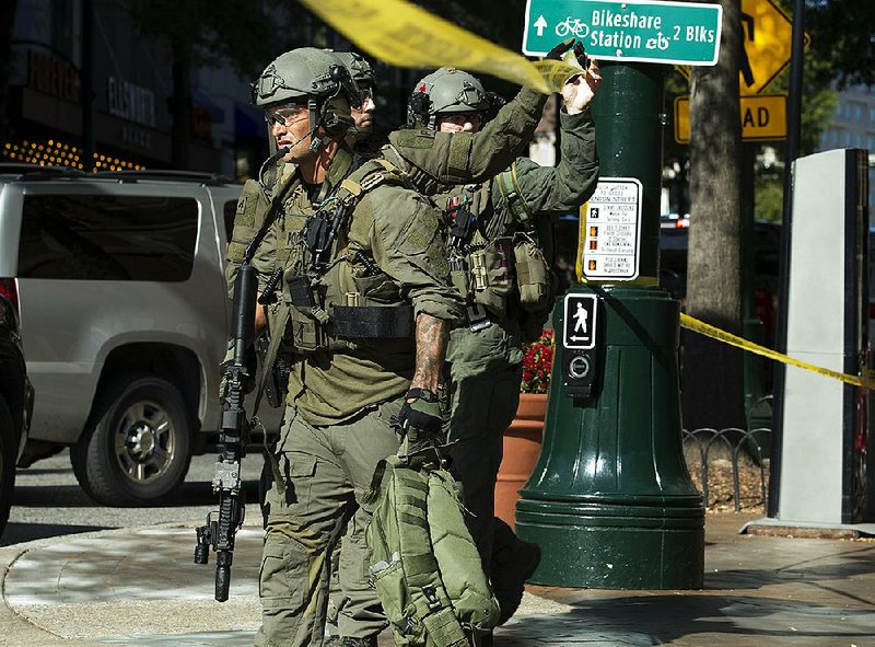 Police officers in tactical gear exit the parking garage where an officer was shot Monday in Silver Spring, Md. 