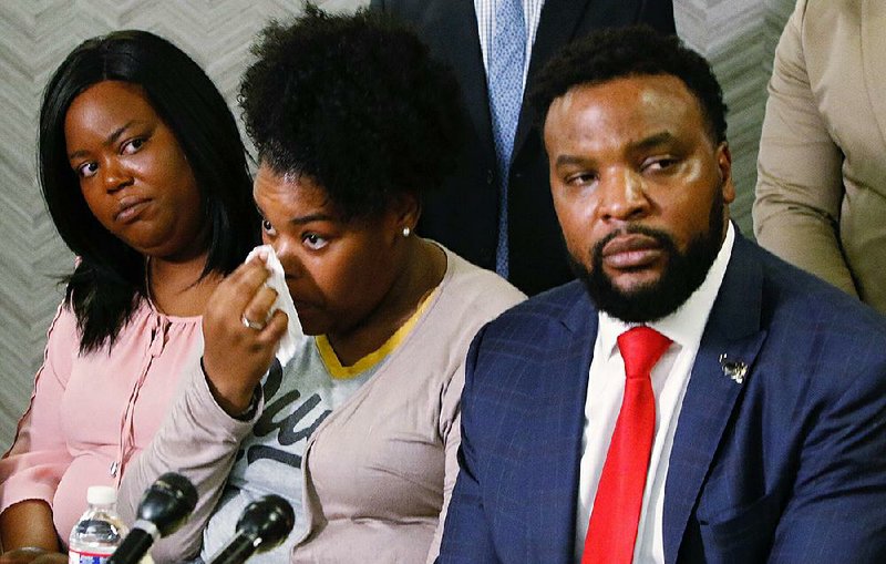 Ashley Carr (from left) and Amber Carr sit with attorney Lee Merritt on Monday during a Dallas news conference about the death of the women’s sister Atatiana Jefferson. More photos are available at arkansasonline.com/1015officer/ 