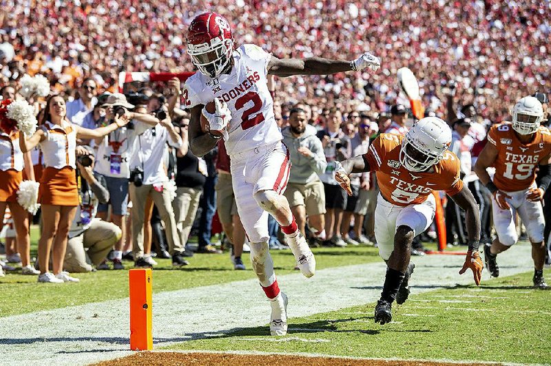 Oklahoma wide receiver CeeDee Lamb scores on his third touch- down reception of the game in front of Texas defensive back D’Shawn Jamison on Saturday at the Cotton Bowl in Dallas. Lamb had 10 catches for 171 yards as the Longhorns gave up 235 yards passing and 276 yards rushing in a 34-27 loss.