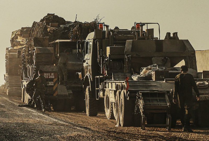 Turkish soldiers work to transport tanks Monday on a road in Sanliurfa province that heads toward the border with Syria. 