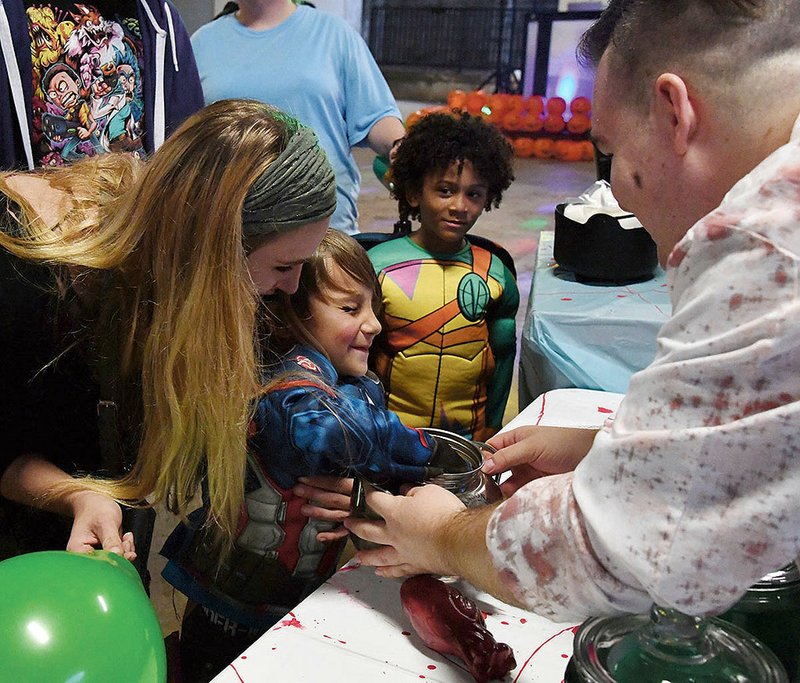 Conrad Canipe, 4, of Hot Springs sticks his hand into a jar of goblin ears at Glow on the Row in downtown Hot Springs on October 31, 2018. - File photo by The Sentinel-Record.