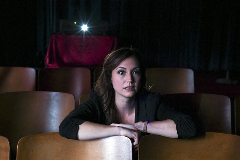 Jen Gerber, director of the Hot Springs Documentary Film Festival, watches part of the first film she made in this photo illustration taken at Low Key Arts. - Photo by Grace Brown of The Sentinel-Record