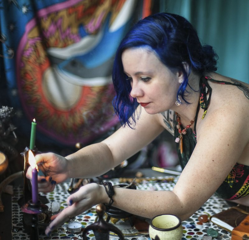 Local Wiccan Karrie Griffin has her photo taken lighting a candle on her altar. - Photo by Grace Brown of The Sentinel-Record. 