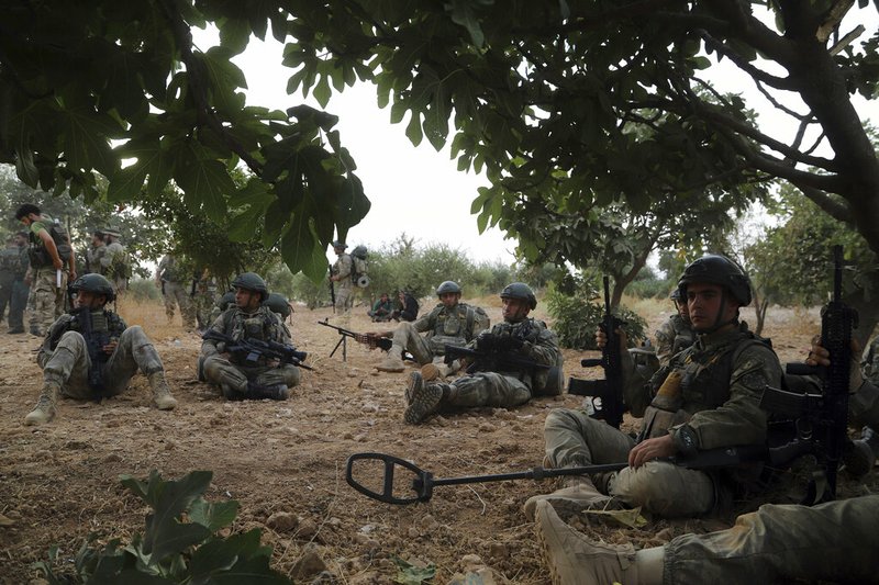 In this Monday, Oct. 14, 2019 photo, Turkish troops rest under trees in Syria's northern region of Manbij. Syrian state media said Tuesday that government forces have entered the center of the once Kurdish-held northern town of Manbij and raised the national flag. (AP Photo)