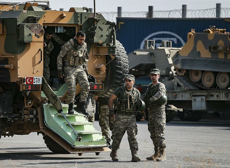 Turkish soldiers prepare to enter Syria Tuesday at Karkamis in southeastern Turkey as Russia announced its forces were on patrol in northern Syria. More photos at arkansasonline.com/1016border/ 