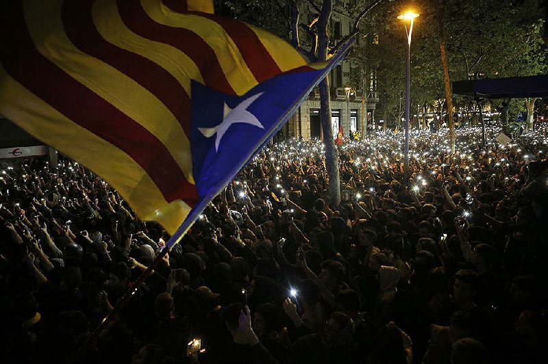 A protester waves a pro-independence Estelada flag Tuesday as other demonstrators hold up their cellphones during a protest in Barcelona, Spain. More photos are available at arkansasonline.com/1016catalan/ 