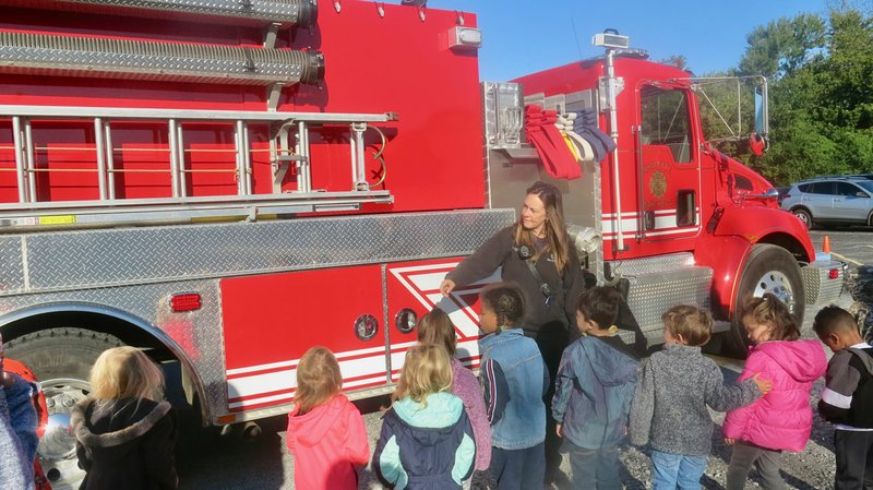 Westside Eagle Observer/SUSAN HOLLAND Firefighter/paramedic Jenni Bohannon points out some of the features on one of Gravette Fire Department's firetrucks during a Fire Safety Week event Tuesday, Oct. 8, at Glenn Duffy Elementary School. The pre-kindergarten students were very interested in learning about the truck's firefighting equipment and how it worked.