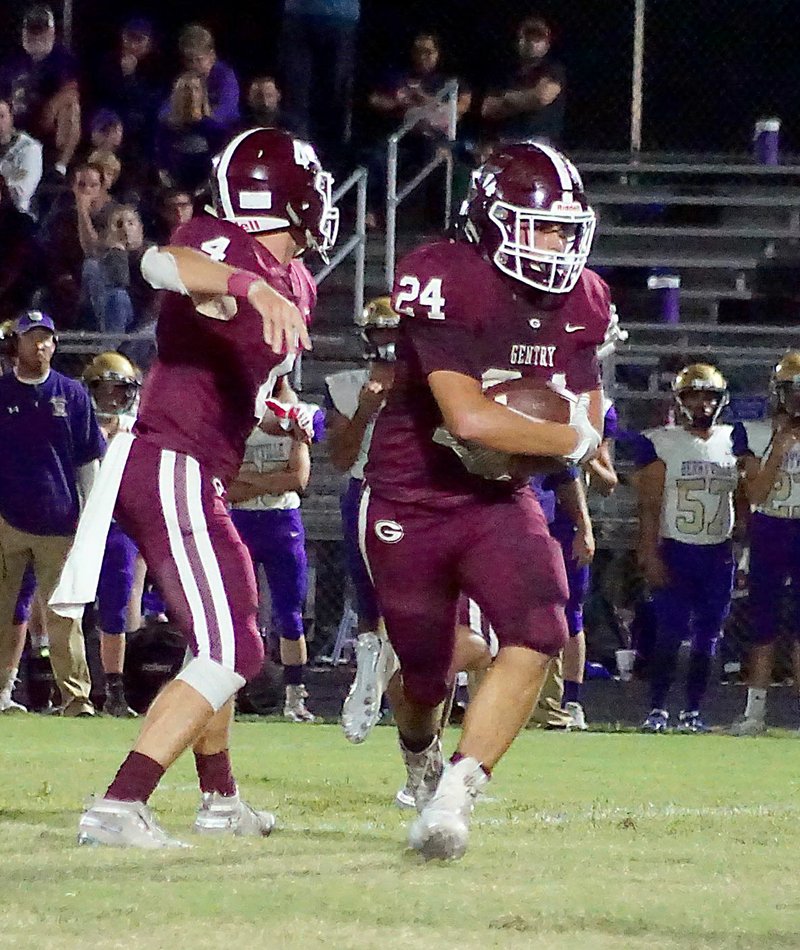 Westside Eagle Observer File Photo/RANDY MOLL Gentry senior quarterback Brandon Atwood hands the ball off to junior Brennan Crosby during play against Berryville on Friday at Gentry High School.