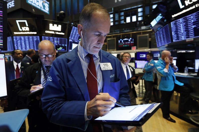 In this Oct. 8, 2019, file photo trader Mark Puetzer, center, works on the floor of the New York Stock Exchange.  (AP Photo/Richard Drew, File)