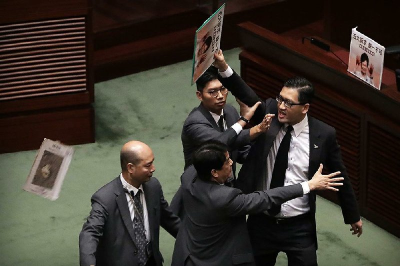 A pro-democracy lawmaker is restrained Wednesday in Hong Kong’s legislative chamber after Hong Kong leader Carrie Lam was forced by hecklers to suspend a key policy address. More photos at  arkansasonline.com/1017hongkong/ 