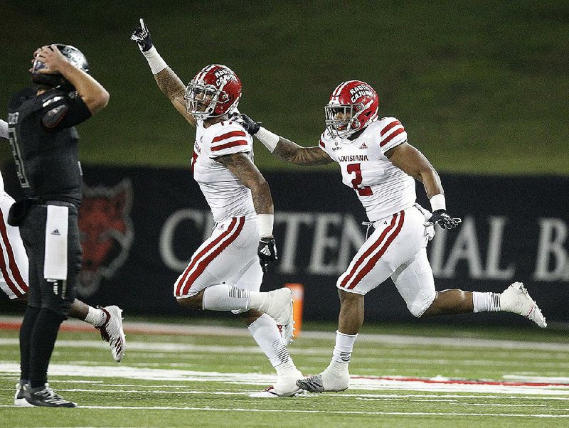 Linebackers Chauncey Manac and Lorenzo McCaskill (2) of Louisiana-Lafayette celebrate in front of Arkansas State quarterback Layne Hatcher after a fourth-down stop during the Ragin’ Cajuns’ victory Thursday night at Centennial Bank Stadium in Jonesboro. See more photos at arkansasonline.com/1018asuvll.