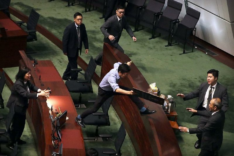 Security officers pursue pro-democracy lawmaker Au Nok-hin as he leaps over desks in the Legislative Council on Thursday to chase Hong Kong Chief Executive Carrie Lam as she leaves a question-and-answer session. 