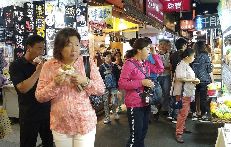 Tourists and natives visit a night market Thursday in Taipei, Tai- wan. 