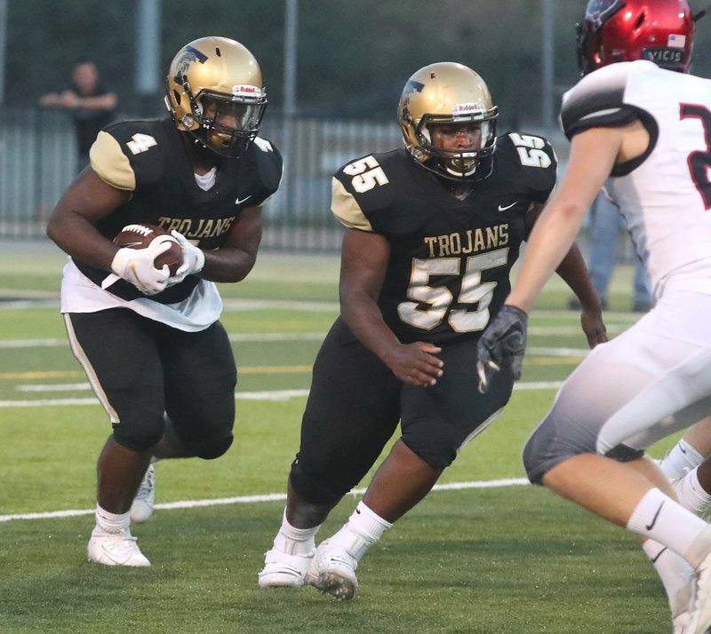 Hot Springs junior running back Carlos Brewer (4) follows blocker Ricardo Hill (55) into the Mena defense on Sept. 13 during the first half at Hot Springs. The Trojans travel to Magnolia tonight. Photo by Richard Rasmussen of The Sentinel-Record