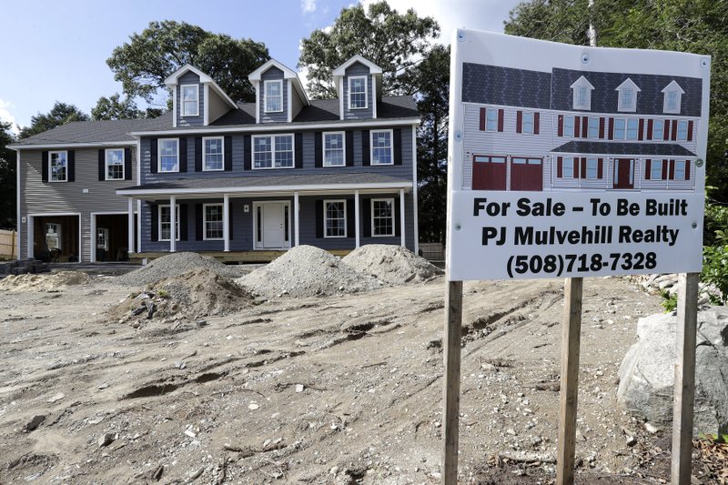 In this Sept. 3, 2019 photo a for sale sign, right, rests in front of a newly constructed home, in Norwood, Mass. On Thursday, Oct. 17, the Commerce Department reports on U.S. home construction in September. (AP Photo/Steven Senne)