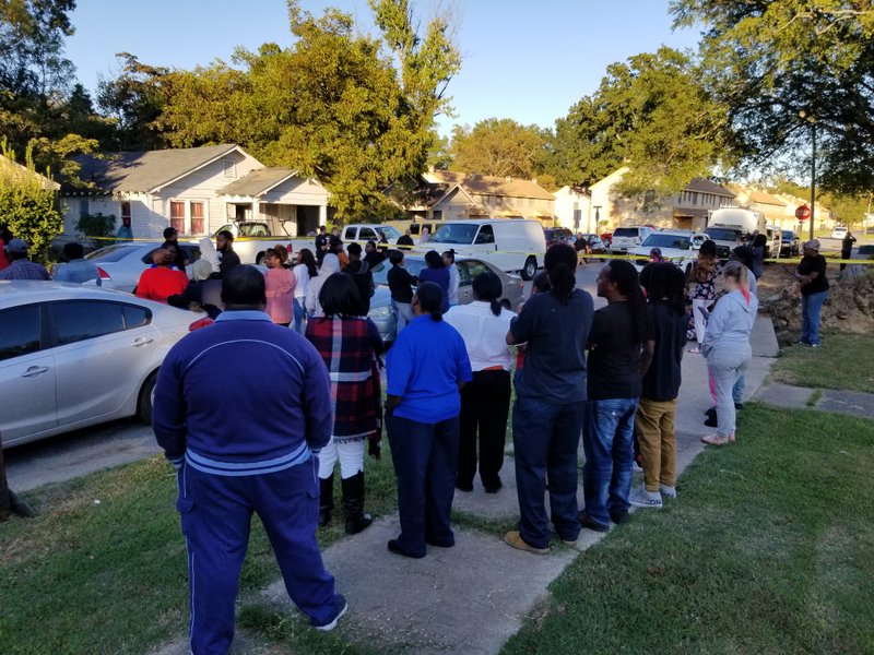 People gather on West 19th Street in North Little Rock as authorities investigate a scene in which two bodies were found Friday evening.
