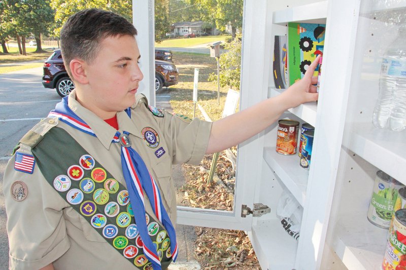 Nicholas Burrell, a ninth-grader at Bryant Junior High School, places some canned goods inside the blessings box he built as his Eagle Scout Project in front of Salem United Methodist Church. Burrell was diagnosed with cancer in April 2017.