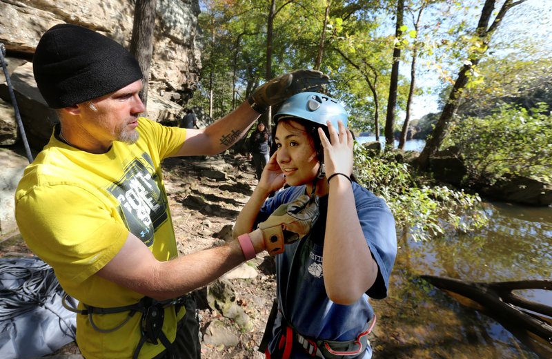 Dasun Keylor, math teacher at Agee Lierly Life Preparations Services: School of Innovation in Fayetteville, checks the fit of a climbing helmet Thursday, October 17, 2019, on Lisbet Lopez, a junior, on a rock climbing field trip to Lake Lincoln. The class was applying math in the real world by recording the height and time of climbs by students and then calculating the speed.