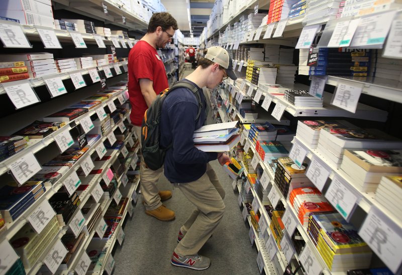 FILE - Edwin Hussey (right), a freshman at the University of Arkansas, receives help Monday, January 16, 2017, from Aaron Naylor, textbook associate at the University of Arkansas Bookstore at the store on campus in Fayetteville. 