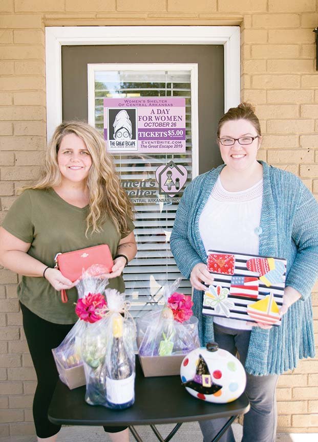 Breanne McClendon, left, executive director of the Women’s Shelter of Central Arkansas in Conway, and Erin Henderson, a member of the shelter’s board of directors, hold items to be auctioned during The Great Escape, a fundraiser scheduled for 10 a.m. to 5 p.m. Saturday at the Conway Expo Center. Henderson is the event chairwoman.