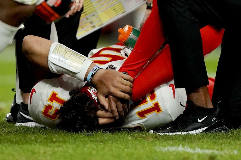 Kansas City Chiefs quarterback Patrick Mahomes (15) holds his head as he is helped by trainers after getting injured in the first half of the Chiefs’ 30-6 victory over the Denver Broncos on Thursday night. Mahomes is expected to miss four to six weeks with a knee injury.