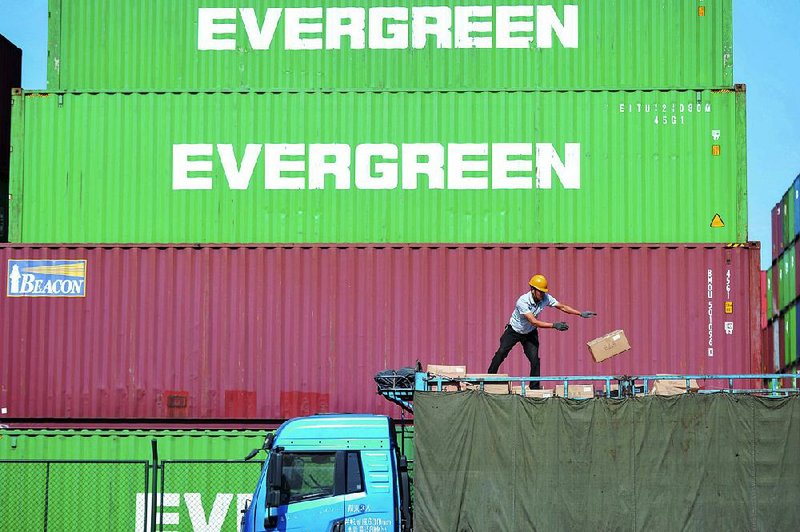 A worker loads imported goods on a truck Monday outside the container port in Qingdao, China. China’s economic growth slipped in the quarter that ended last month. 
