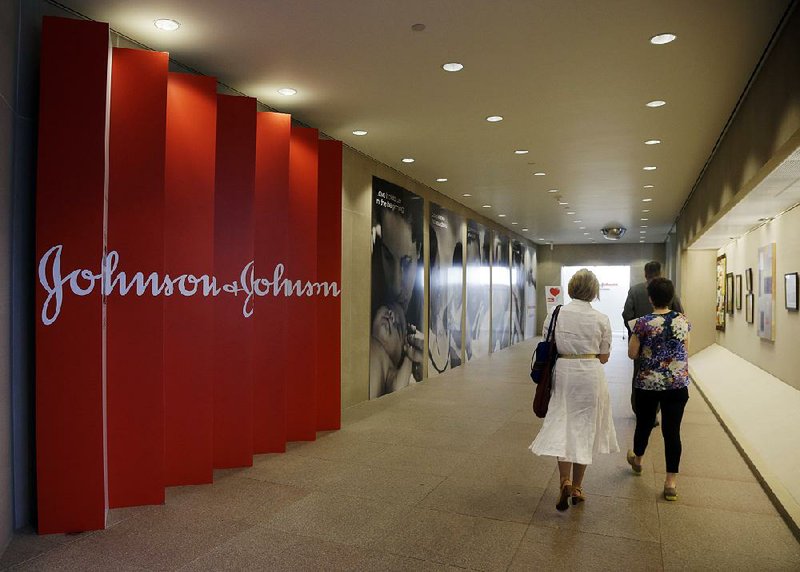 People walk inside the Johnson & Johnson headquarters building in New Brunswick, N.J. The company is recalling 33,000 bottles of its baby powder. 