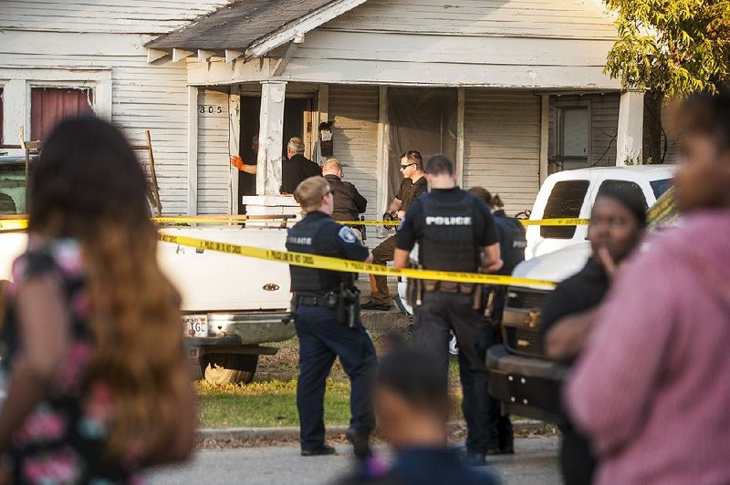 A crowd forms outside of a house Friday in North Little Rock where police found two bodies.