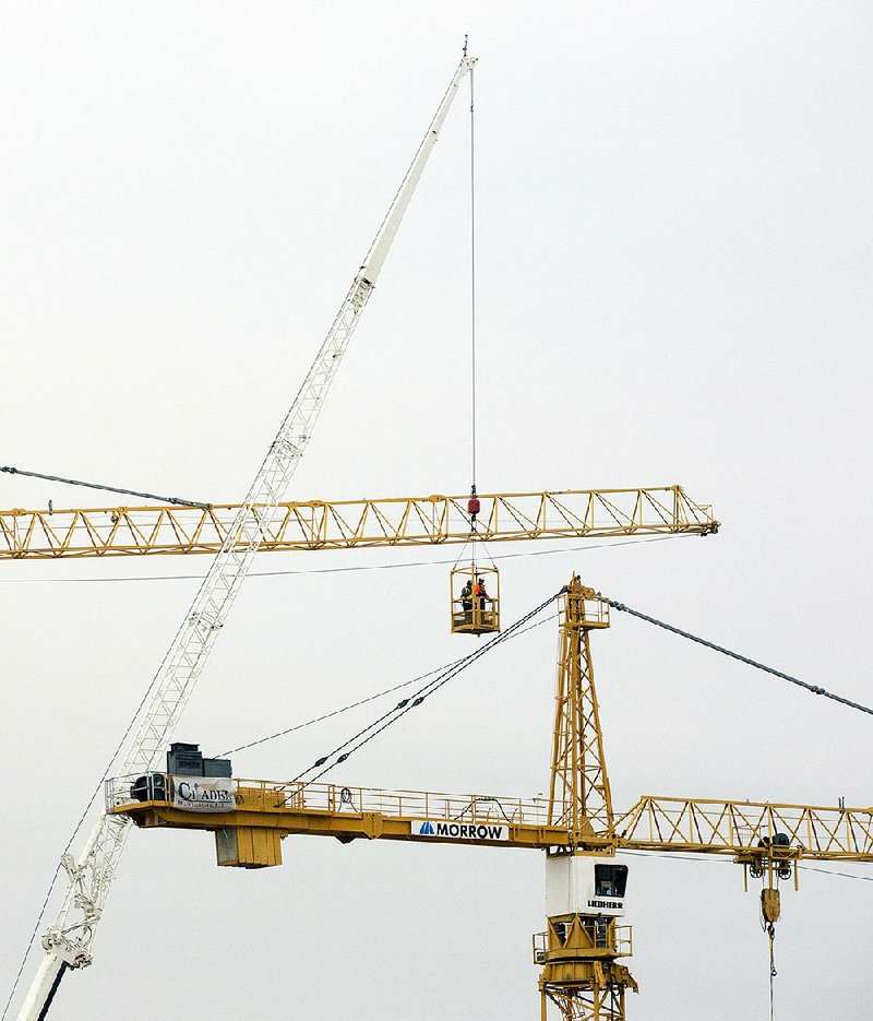 Workers inspect the two unstable cranes Friday at the Hard Rock Hotel construction site in New Orleans. 