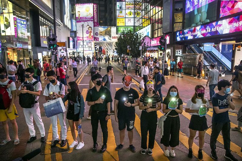 Protesters wearing masks stand along a commercial shopping street Friday in Hong Kong. 