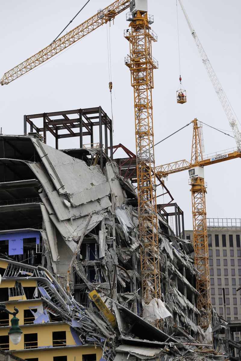 Workers in a bucket hoisted by a crane begin the process of preparing the two unstable cranes for implosion at the collapse site of the Hard Rock Hotel, which underwent a partial, major collapse while under construction last Sat., Oct., 12, in New Orleans, Friday, Oct. 18, 2019. Authorities plan to blow up the two towering construction cranes that have become unstable at the site of the collapsed hotel. They hope to bring down the cranes with series of small controlled blasts just ahead of approaching tropical weather. The mayor has imposed a state of emergency to seize property and force people out if necessary. They hope to avoid more damage to gas and power lines and historic buildings. (AP Photo/Gerald Herbert)