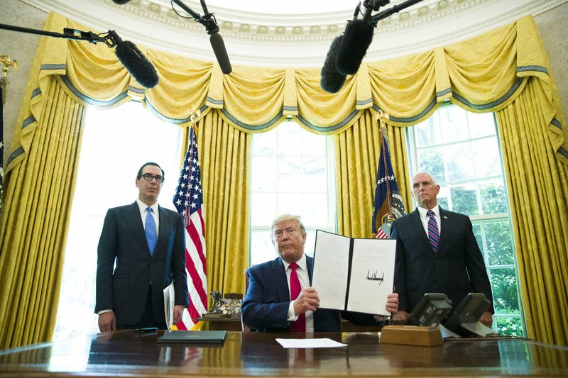 FILE - In this June 24, 2019, file photo, President Donald Trump holds up a signed executive order to increase sanctions on Iran, in the Oval Office of the White House in Washington, with Treasury Secretary Steven Mnuchin, left, and Vice President Mike Pence. Trump is now three for three. Each year of his presidency, he has issued more executive orders than did former President Barack Obama during the same time-span. (AP Photo/Alex Brandon, File)