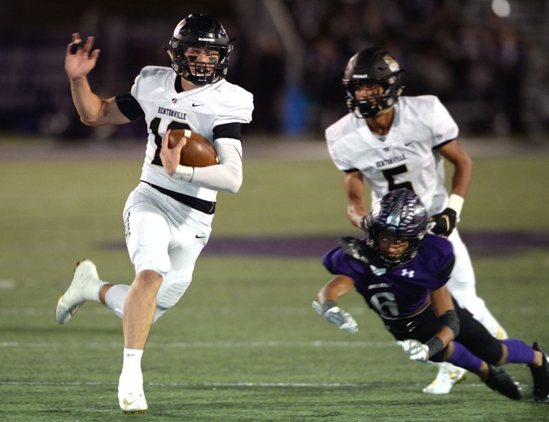 Bentonville quarterback Ben Pankau (10) carries the ball Friday, Oct. 18, 2019, past Fayetteville defensive back Taveon Williamson (6) during the first half of play at Harmon Stadium in Fayetteville.