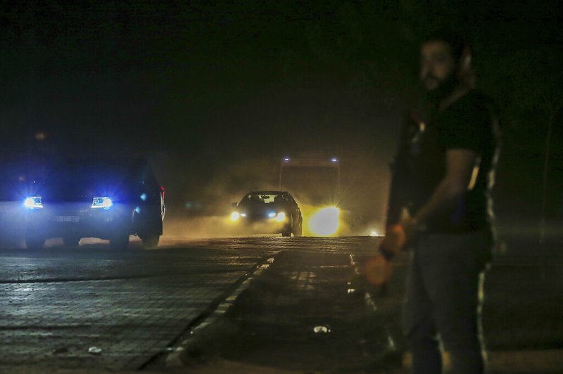 In this late Friday, Oct. 18, 2019 photo, Turkish police and army cars escort vans and buses returning from Syria, reportedly carrying IS group members and their families, at the border town of Akcakale, Sanliurfa province, southeastern Turkey. 