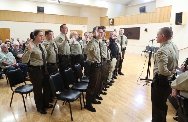 Class leader Jeremy Rowland, right, administers the oath of office to his classmates at the Garland County Sheriff's Department Auxiliary badge pinning ceremony on Friday.