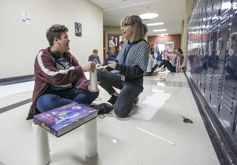 NWA Democrat-Gazette/BEN GOFF &#8226; @NWABENGOFF Eli Steinhour and Alyssa Hanshew, both seniors, build a table Thursday during their physics class at Har-Ber High School in Springdale. Students in the class were tasked with building a table from only paper and tape that would be strong enough to support a textbook. Steinhour and Hanshew built the strongest table in the class. Their design was able to support 33 textbooks.