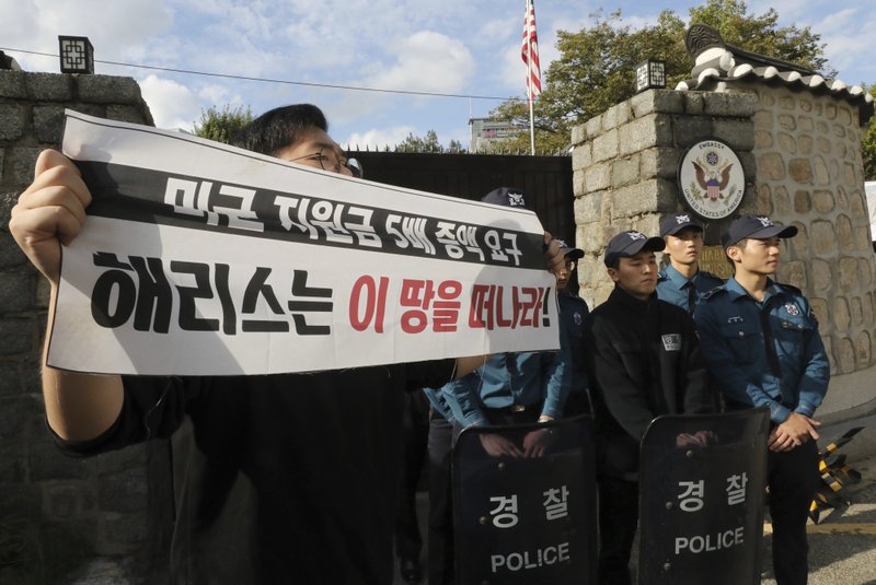 In this Friday, Oct. 18, 2019, photo, a college student holds a banner in front of the U.S. ambassador's residence in Seoul, South Korea. South Korean police said Saturday, Oct. 19, they beefed up security at the U.S. ambassador's residence in Seoul after a group of anti-American students used ladders to break into the compound.  (Chun Jin-hwan/Newsis via AP)