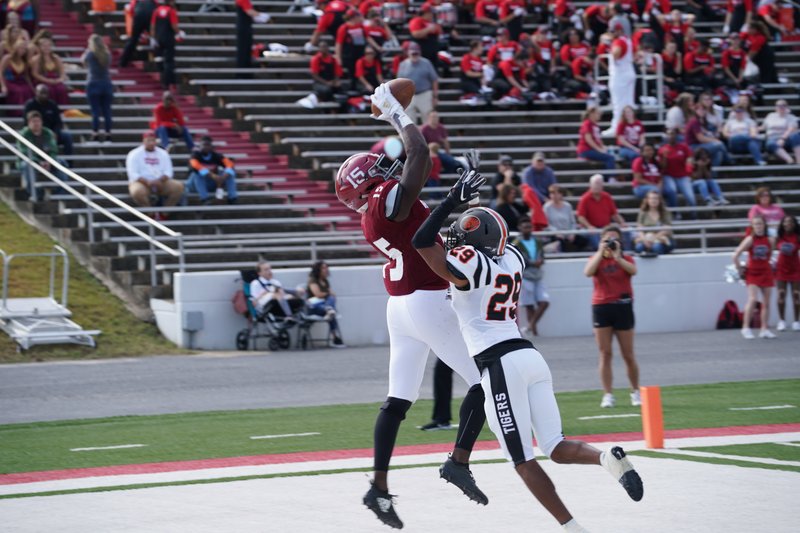 Henderson State senior receiver L’liott Curry (15) snags a pass from quarterback Richard Stammetti in Saturday’s game against East Central as Martinez Hill (29) defends. The Reddies won, 48-17. Photo courtesy of Reddies Athletics