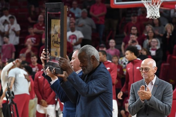 Former head coach for the Razorbacks basketball team Nolan Richardson (center) holds a plaque with athletic director Hunter Yurachek while University of Arkansas chancellor Joseph Steinmetz applauds (right) Sunday, Oct. 20, 2019, after the court at Bud Walton Arena in Fayetteville was named after Richardson.