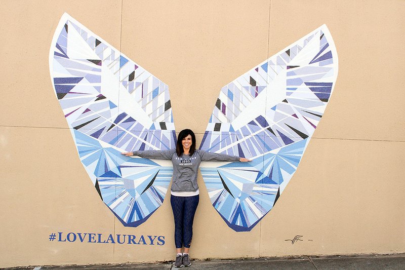 Daresa Rhine, while visiting Hot Springs from Texas, recently stood in front of the new angel wing mural on the side of Lauray's The Diamond Center. - Photo by Tanner Newton of The Sentinel-Record