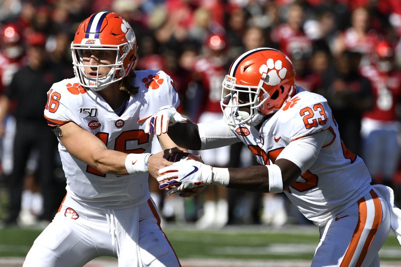Clemson quarterback Trevor Lawrence (16) hands the ball off to running back Lyn-J Dixon (23) during the first half of Saturday's game against Louisville in Louisville, Ky. Photo by Timothy D. Easley of The Associated Press