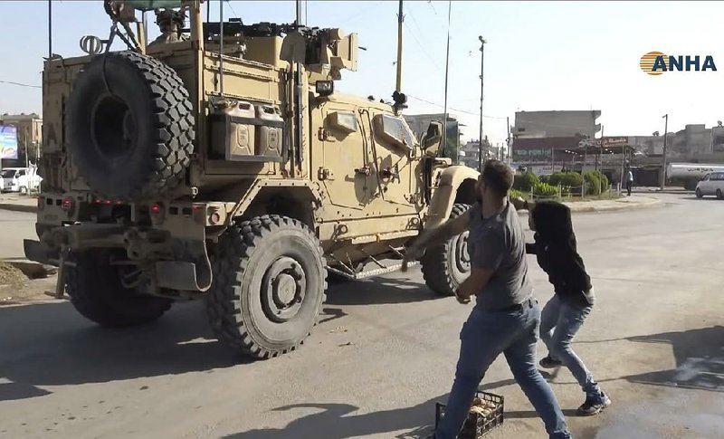 Residents throw potatoes at an American military vehicle as it passes through Qamishli, Syria, on Monday. More photos are available at arkansasonline.com/1022iraq